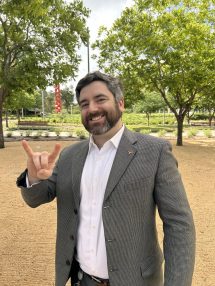 A headshot of Michael Cronin with a Hook 'em Hand