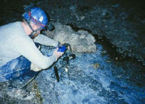 Taking environmental measurements in cave stream with mats.