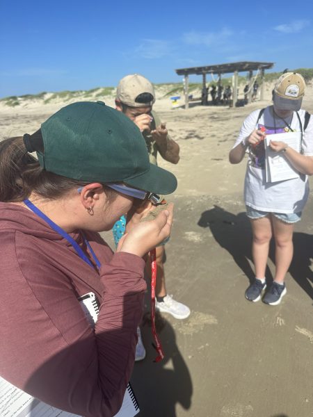 GeoFORCE participant using a hand lens donated by ExxonMobil to study grain size at Mustang Island State Park in Corpus Christi, Texas.