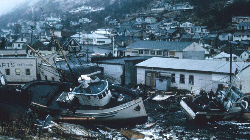 A fishing boat sits among litter strewn streets and damaged buildings..