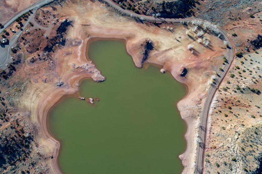 An aerial shot of a green lake with red rings around its contours, indicating that the levels are lower than usual.