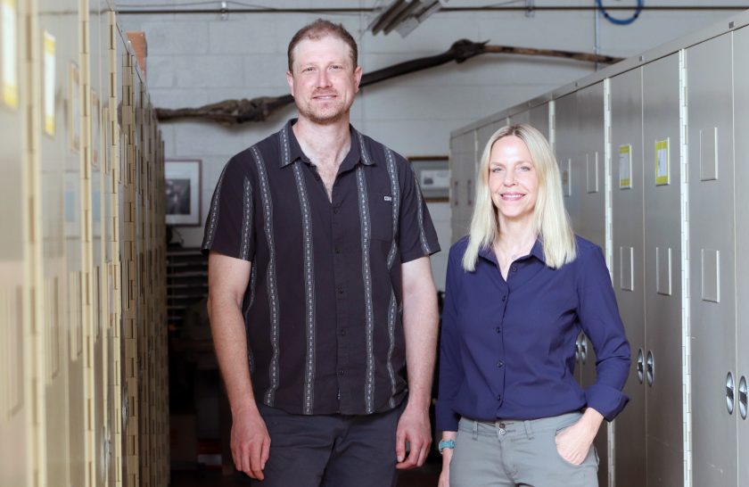 Paleontologists Ben Kligman and Lisa Boucher stand amongst collection cabinets at the Vertebrate Paleontology laboratory