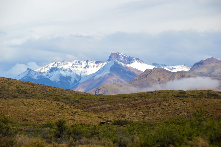 Mountain peaks rise above a green meadow