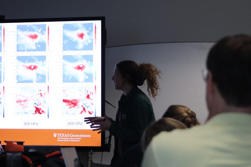 A backlit woman stands in front of a screen with climate models displayed.