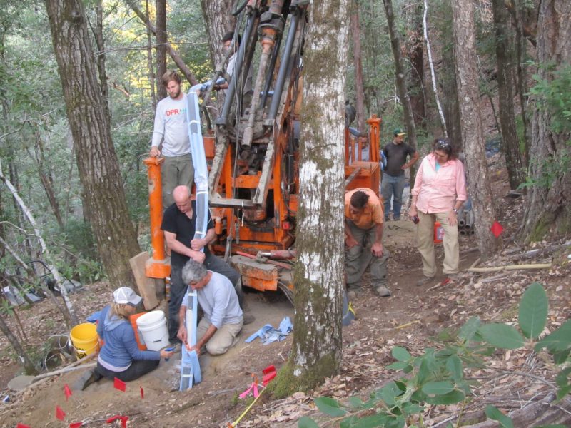Picture of scientists using a large coring drill in the forest.