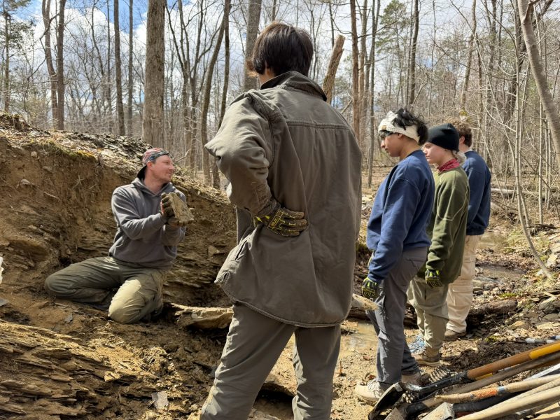 Ben Kligman showing a fossil to four students 