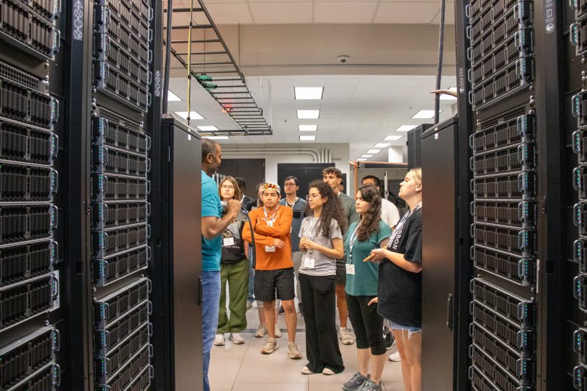 RTX students stand at the end of a dark hallway of computers.