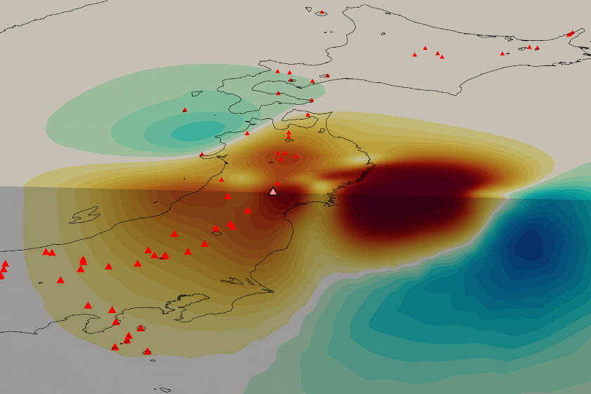 The figure is a cutaway drawing of Japan showing large redish patches beneath the country, and cooler, blue colors surrounding it. The figure includes markers for a line of volcanoes running the length of Japan.