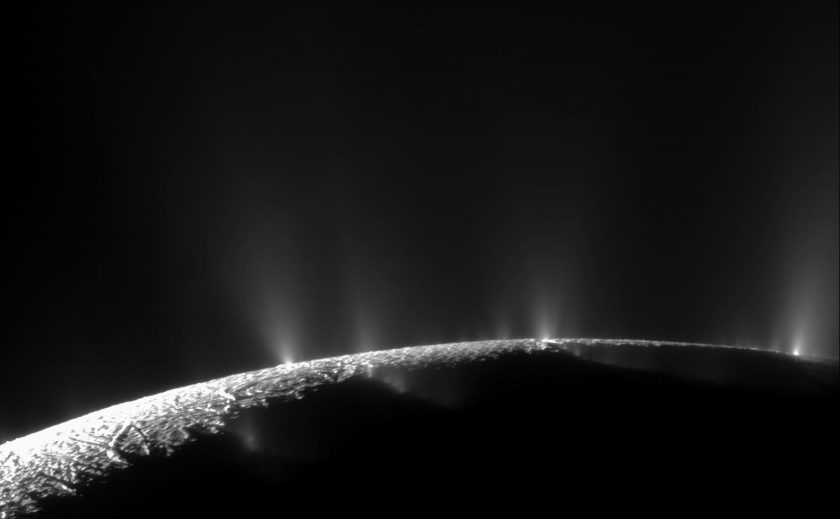 Black and white image of moon's surface showing several plumes spraying mist-like material into space.