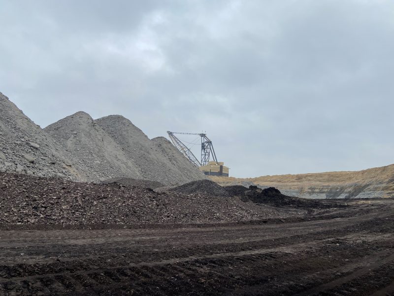 Piles of coal with heavy machinery in the background