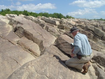 The bureau’s Chock Woodruff, a geologist, studying an outcrop of Smithwick sandstone along the upper reaches of Lake Travis.