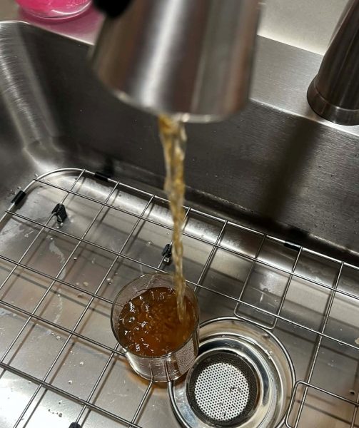 Discolored water runs from a water tap into a glass