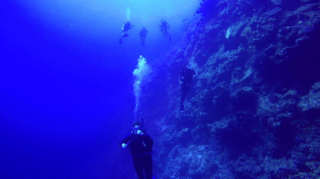 Group drops over wall at Grouper Gulley. Sheer drop here, no upper slope talus in sight.