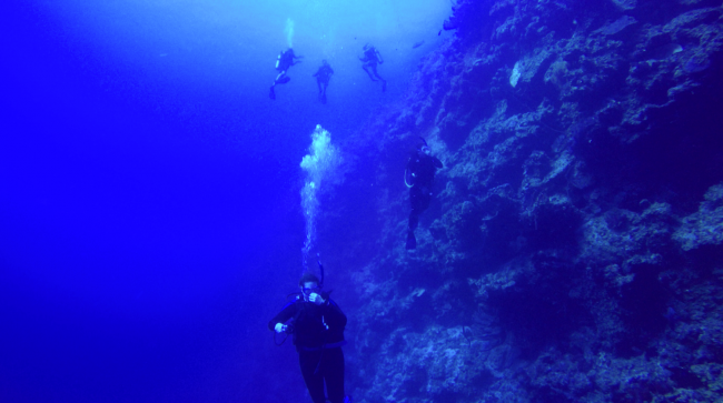 Group drops over wall at Grouper Gulley. Sheer drop here, no upper slope talus in sight. 